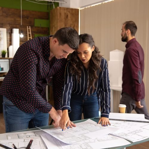 Two fellow architects standing at the table and discussing the project. Modern office