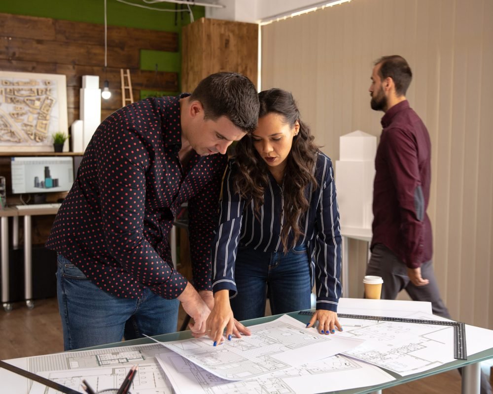 Two fellow architects standing at the table and discussing the project. Modern office